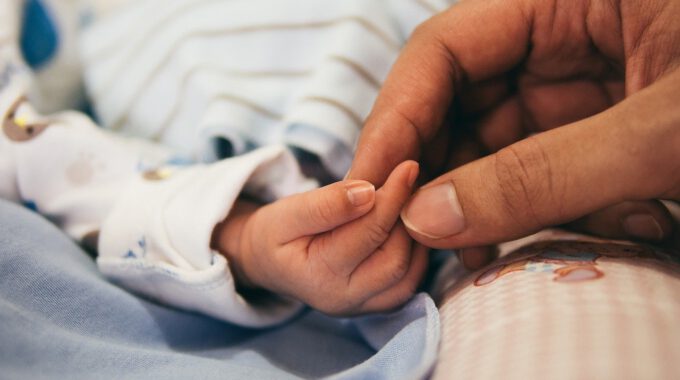Mutter hält die Hand eines Säuglings