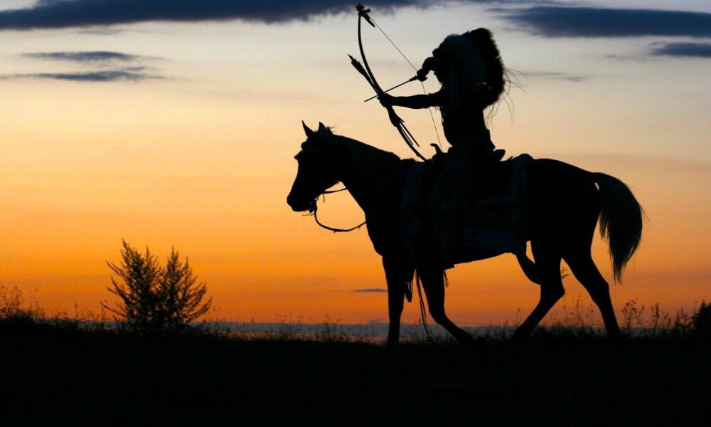 Indianer zu Pferd zielt mit seinem Bogen