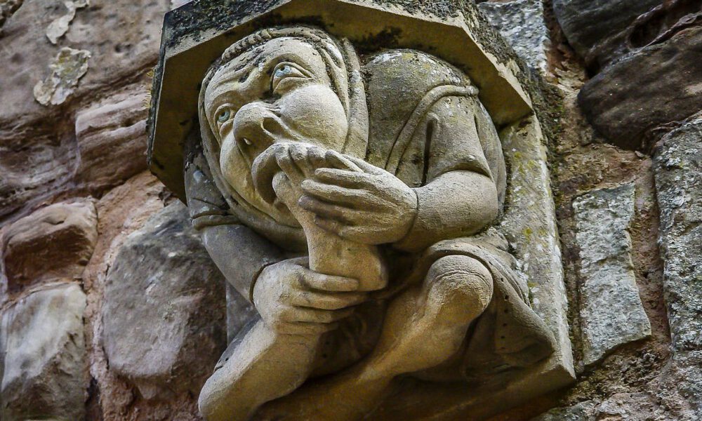 Mittelalterlicher Wasserspeier, der sich den großen Zeh in den Mund steckt