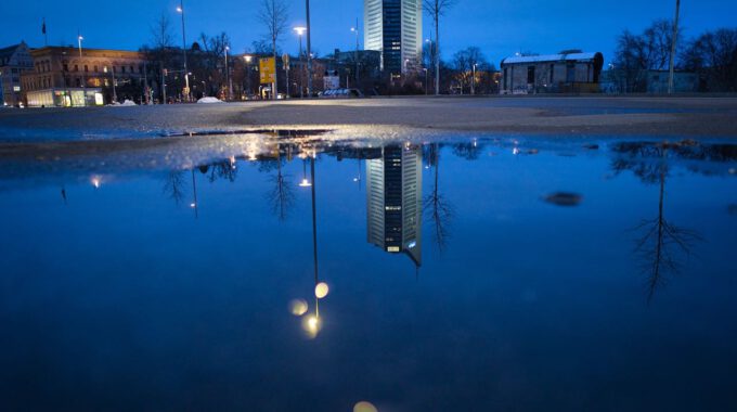 Der Leipziger Uniriese spiegelt sich in Regenwasser.
