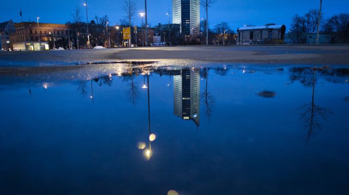 Der Leipziger Uniriese Spiegelt Sich In Regenwasser.