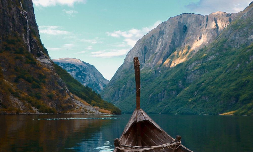 Ein Wikingerschiff läuft in einen Fjord ein - rechts und links hohe Berge